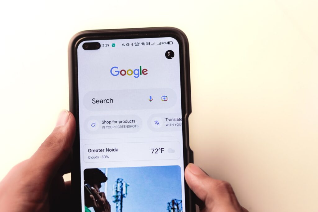 How to Get Found on Google and AI Search in 2026 how to get found on Google and Ai search, A close-up of a hand holding a smartphone with Google search displayed on the screen.
